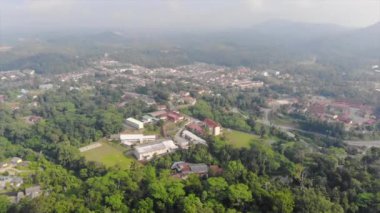 Small Buildings Surrounded By Tropical Forest With Mountains In The Background - Dolly Backwards
