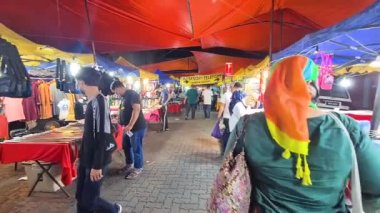  Dışarıdaki Gece Pazarı 'nda, renkli çadırlarla çevrili cerrahi maske takan insanlar.