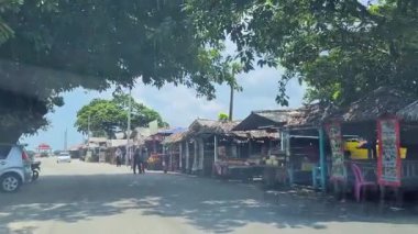 Sahilde yerel Malezya sokak yiyecekleri satan ağaçtan yapılmış küçük barakalar ve palmiye yaprakları.