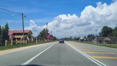 Gökyüzünde büyük beyaz bulutlarla Malezya 'da küçük bir kasabadan geçmek