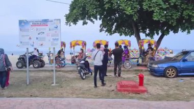 Sahildeki kaldırımda soldan sağa dönen renkli vagon trenleri..