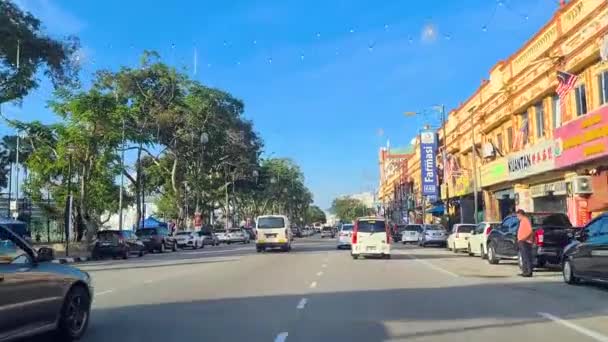 明るい青色の日に側に沿ってカラフルなお店がたくさんあるクアンタンの通りを運転する Dolly Forward — ストック動画