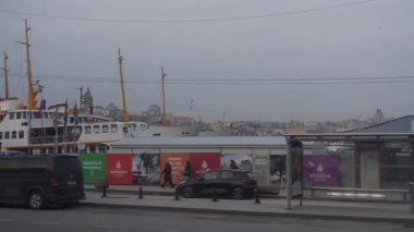 Limana yakın taksiler, inşaat alanı arkada, sağdan sola kayan insanlar ve binalar..