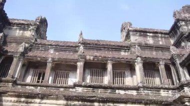 Etrafı eski kaya binalarıyla çevrili insanlar soldan sağa dönüyor.