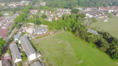 Etrafında ağaçlar olan küçük bir köyün ortasında boş bir futbol sahası.