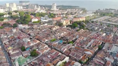  Mavi okyanusun ve yeşil ağaçların doğal renkleri arasında kalabalık bir şehir Sağdan sola kıvrılıyor.