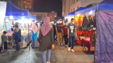 Yerel Malezyalılar, Covid-19 sırasında Melaka 'da Gece Pazarı' nda maske takarak dolaşıyorlar.