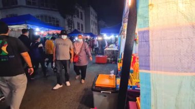  Yerel Malezyalılar bir gece pazarında maske takarak dolaşıyorlar.
