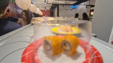 Malezya 'daki bir Japon restoranındaki taşıma bandından suşi geliyor.
