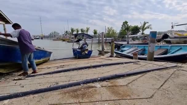 漁師がボートハウスで停泊船を通って行く — ストック動画