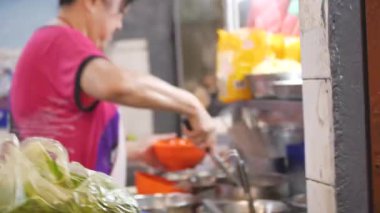 Yaşlı Çinli kadın bir kase çorba servis ediyor. 