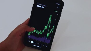 Woman looking through BNB 1 Month chart on Black smartphone