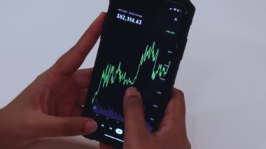 Woman looking through BTC 6 Months chart on Black smartphone