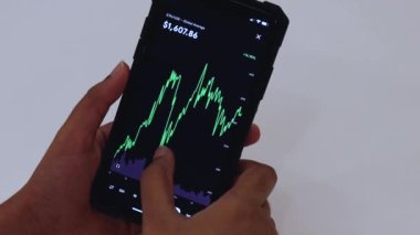 Woman looking through ETH 1 Month chart on Black smartphone
