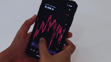 Woman looking through ETH 1 Week chart on Black smartphone