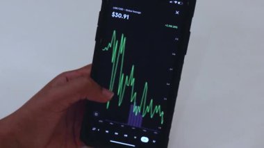 Woman looking through LINK 2 Years chart on Black smartphone