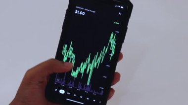 Woman looking through USDT 1 hour chart on Black smartphone