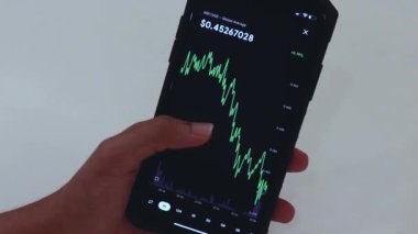 Woman looking through XRP 1 Hour chart on Black smartphone