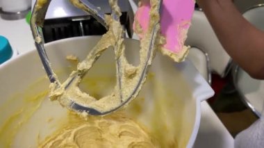 Ev yapımı tereyağlı kek hamuru dolu karıştırma kabını kazıyorum. 