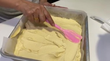 Kare tavaya silikon spatula kullanarak pasta hamuru yaymak