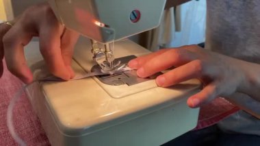 Kadın jartiyer dikmek için eski dikiş makinesini kullanıyor. Kapat.