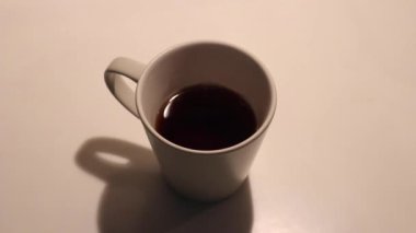 Bir çay kaşığı şekeri sade kahveyle bardağa koyuyorsun.