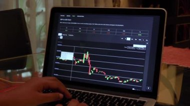 Woman going through XRP 14 days Candle Stick Charts on a Laptop
