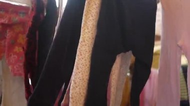 Çarşıda asılı kumaş tamir eden biri.