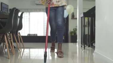 Afro kadın dans ediyor ve yerleri paspaslıyor.