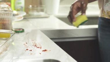 Afro kadın mutfak üstünü süngerle temizliyor.
