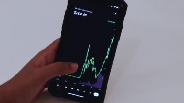 Woman looking through BNB 3 Years chart on Black smartphone