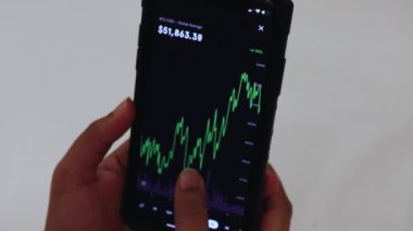Woman looking through BTC chart on Black smartphone
