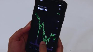 Woman looking through BTC charts on cellphone