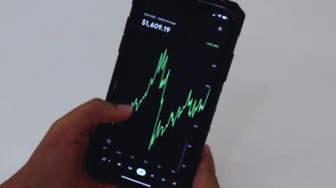 Woman looking through ETH 6 Months chart on Black smartphone