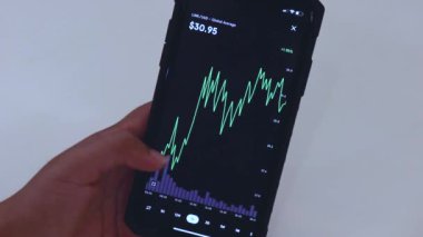 Woman looking through LINK 1 Day chart on Black smartphone