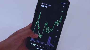 Woman looking through LINK 1 hour chart on Black smartphone