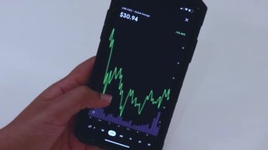 Woman looking through LINK 3 Months chart on Black smartphone