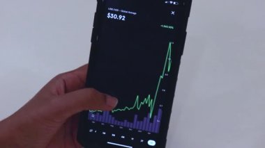 Woman looking through LINK 3 Years chart on Black smartphone