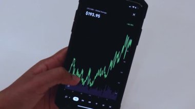 Woman looking through LTC 1 Month chart on Black smartphone