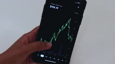 Woman looking through LTC 1 Hour chart on Black smartphone