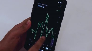 Woman looking through LTC 2 years chart on Black smartphone