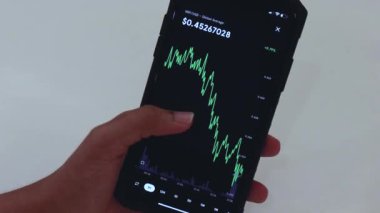 Woman looking through XRP 1 Hour chart on Black smartphone