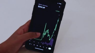 Woman looking through BNB 3 Years chart on Black smartphone