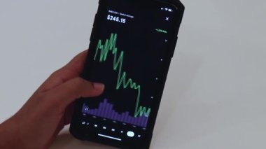 Woman looking through BNB 2 Years chart on Black smartphone