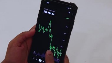 Woman looking through BTC 12 Hours chart on Black smartphone