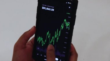 Woman looking through BTC chart on Black smartphone