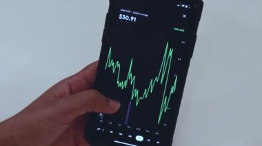 Woman looking through LINK 1 Year chart on Black smartphone