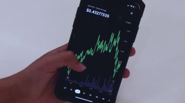 Woman looking through XLM 12 hours chart on Black smartphone