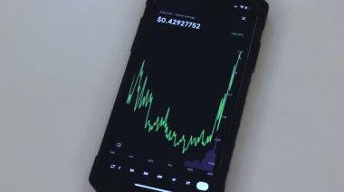 XLM Stellar chart on a black phone placed on a white table