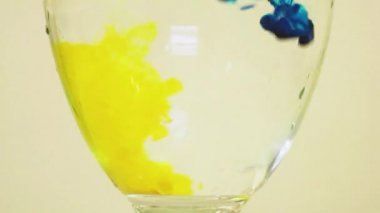 Color Dyes Being Added Into Wine Glass - Blue And Light Yellow.